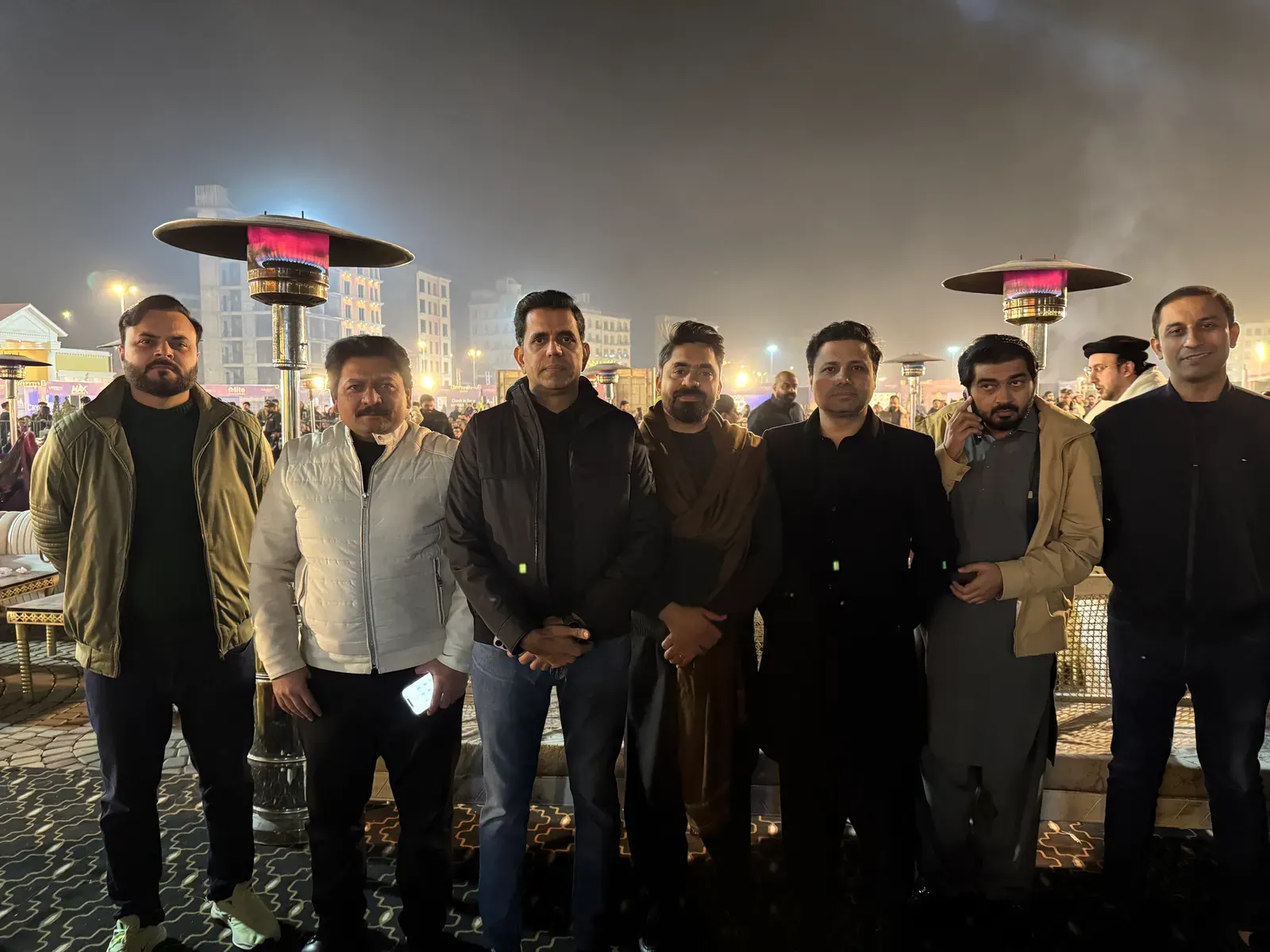 Casual outdoor evening gathering with heaters at a project site.